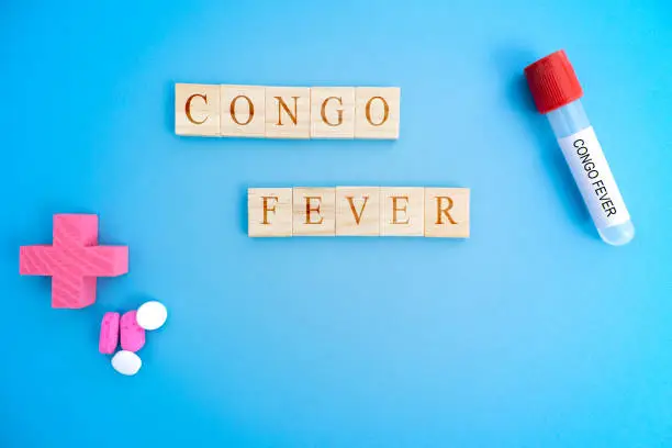 Photo of Cocept of Crimean Congo hemorrhagic fever, congo Fever or CCHF in wooden block letters with laboratory tubes.