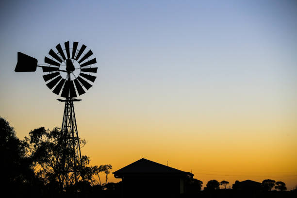 Vintage windmill silhouette against sunset. Silhouette of house, village, trees