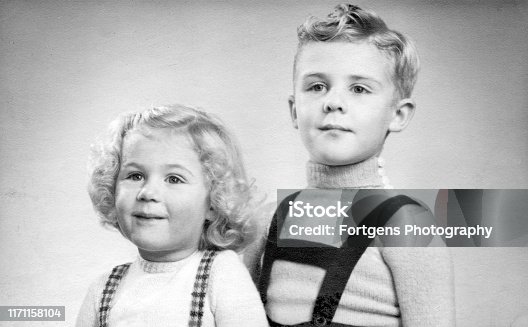 istock Early 1950s duo portrait of a young boy and girl with blond hair and curls. 1171158104
