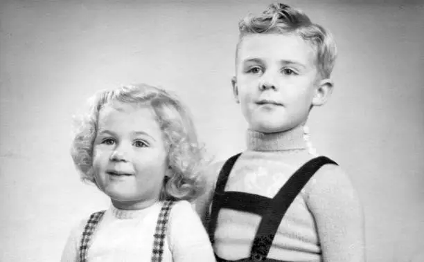 Photo of Early 1950s duo portrait of a young boy and girl with blond hair and curls.