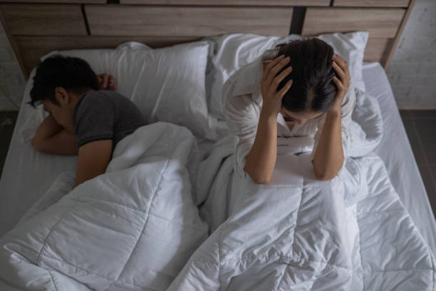 Asian couple in bed, they quarrel. They are not happy they stock photo