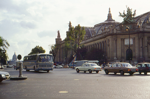 PARIS / FRANCE - MAY 1975: Analog atmospheric  vintage image of cars and buses crossing the Champs-Elysées near the Grand Palais in the heart of Paris.