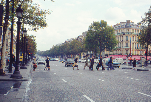 PARIS / FRANCE - MAY 1975: Analog atmospheric vintage image of people crossing the boulevard Champs-Elysées.