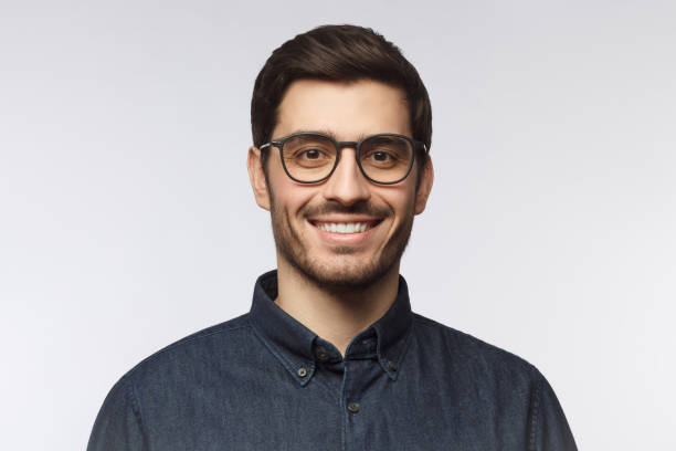 headshot de l'homme beau gai avec la coupe de cheveux et les lunettes à la mode d'isolement sur le fond gris - men fashion model cool glasses photos et images de collection