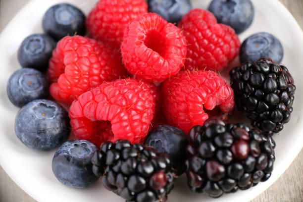 istock Berries: blackberries, blueberries, rasberries on a white wood background 1171170073
