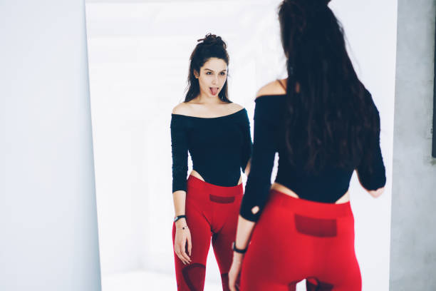 istock Attractive brunette woman in tracksuit making funny face looking at mirror on training break,slim sporty girl satisfied with reflection of her perfect body shape keeping active lifestyle keeping fit 1171171211