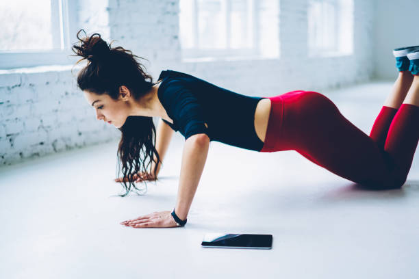 istock Determined woman doing push ups exercises for training chest and arms muscles in white interior gym,slim strong girl planking from knees having hard workout for keeping athletic body shape 1171171281