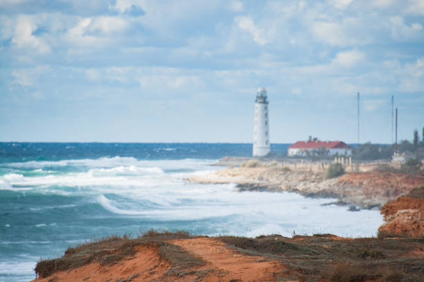 istock beautiful seascape with sea shore on foreground and white lighthouse on background during storm weather with high waves 1171171521