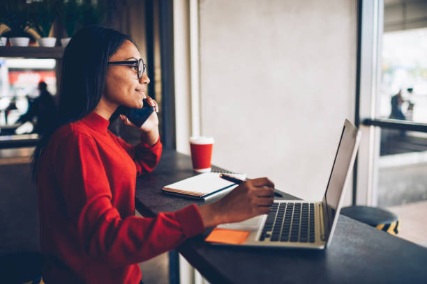 istock Professional afro american copywriter talking about new project on mobile earning money online.Attractive dark skinned manager in stylish spectacles checking banking account talking with operator 1171171984