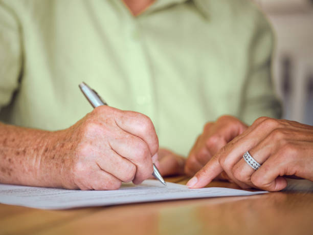 istock Senior Woman Signing Documents in Her Home 1171173272