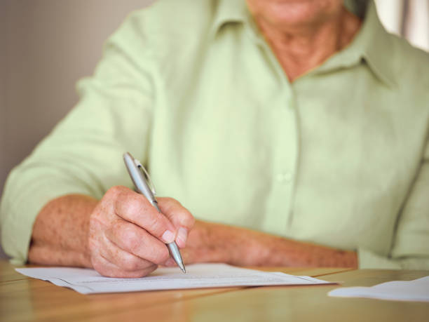 istock Senior Woman Signing Documents in Her Home 1171173389