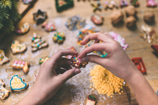 istock female hands decorating christmas cookie at wooden table 1171176056