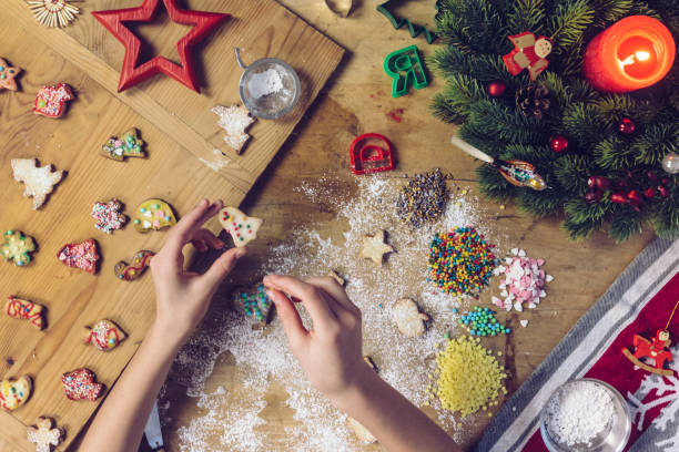 istock female hands decorating christmas cookie at wooden table 1171176084