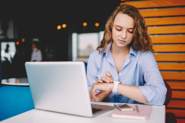 istock Serious female freelancer checking time on electronic smartwatch while waiting for meeting with colleague in cafeteria, young woman tracking gps via wristwatch during distance job in coworking space 1171176201