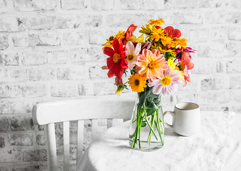 Bouquet of bright colorful autumn flowers on a bright table in a cozy light kitchen. Copy space, flat lay