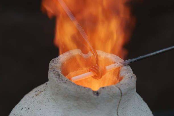 Glassblower in the work Photography of the process of making beads in the workshop. Man glassblower make handmade products under burner. Ancient Slavic technique depends on bellows fanning. hand blown glass stock pictures, royalty-free photos & images