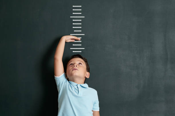 Child measuring his height on wall. He is growing up so fast. stock photo