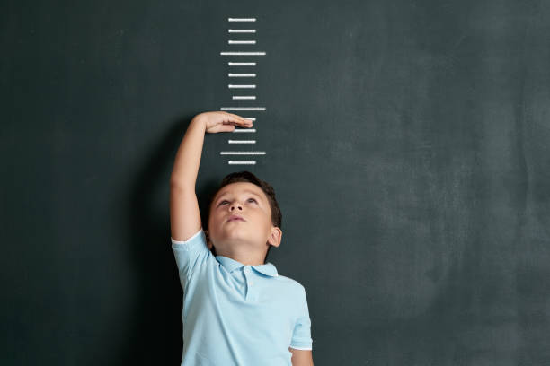 Child measuring his height on wall. He is growing up so fast. Child measuring his height on wall. He is growing up so fast. one little boy stock pictures, royalty-free photos & images