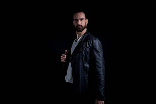 istock Handsome man wearing leather jacket and white shirt on black background 1171181435