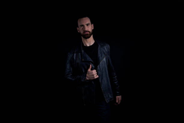 istock Good looking man wearing black tshirt and leather jacket on black background 1171182025