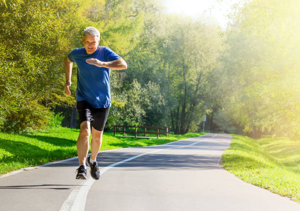 istock Active middle aged man running in public park 1171182391