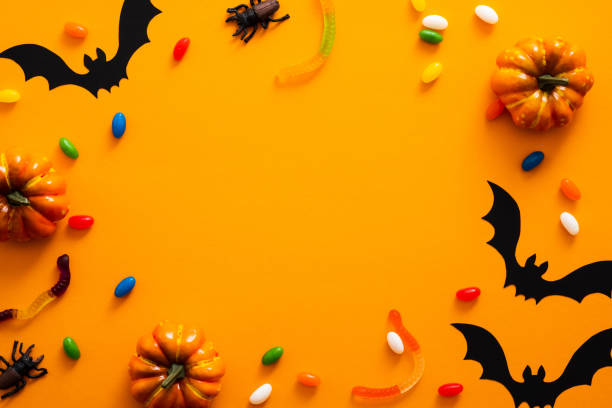 istock Happy halloween holiday concept. Halloween decorations, pumpkins, bats, candy, bugs on orange background. Halloween party greeting card mockup with copy space. Flat lay, top view, overhead. 1171184629