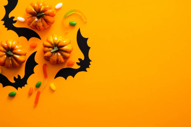 istock Happy halloween holiday concept. Halloween decorations, pumpkins, bats, candy, ghosts, bugs on orange background. Halloween party greeting card mockup with copy space. Flat lay, top view, overhead. 1171184672