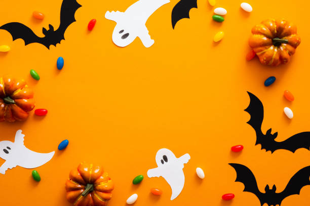 istock Happy halloween holiday concept. Halloween decorations, pumpkins, bats, candy, ghosts, bugs on orange background. Halloween party greeting card mockup with copy space. Flat lay, top view, overhead. 1171184715