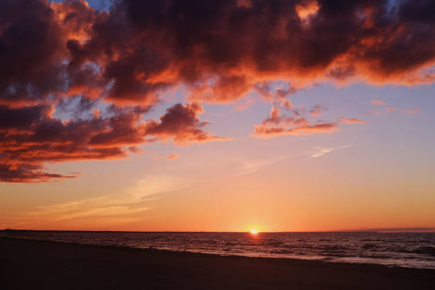 Setting sun, calm sea and colourful clouds at the seaside on a dusk time.