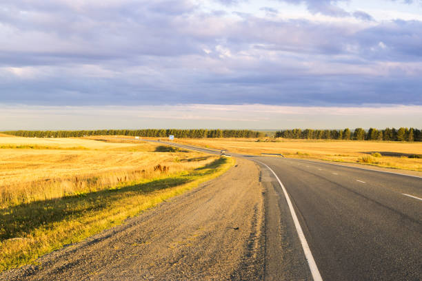 Sunny autumn day for travel on a road among fields