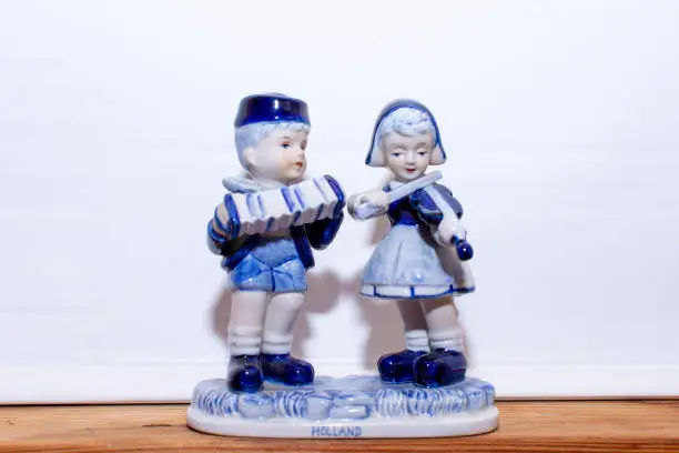 Photo of Delft Blue Figurine of Dutch couple playing music on a violin and accordion. Souvenir from Holland/Netherlands. Isolated on white background.