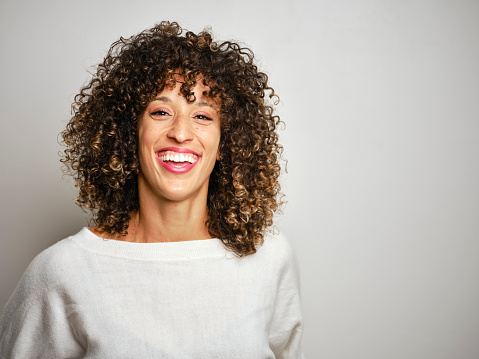 A portrait of a natural mixed race young woman against a white background.