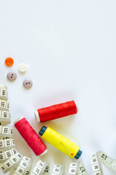istock Sewing accessories. Flat lay of spools of colored thread, pin, centimeter and buttons on white background. Copy space 1171196594
