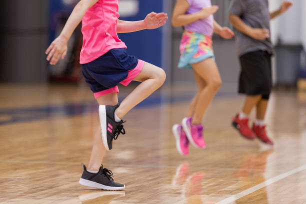 Young children do cardio exercises Unrecognizable elementary students warm up before PE class. running shoes on floor stock pictures, royalty-free photos & images