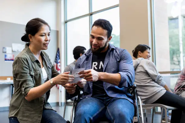 Photo of Mid adult woman and army vet in wheelchair review handout