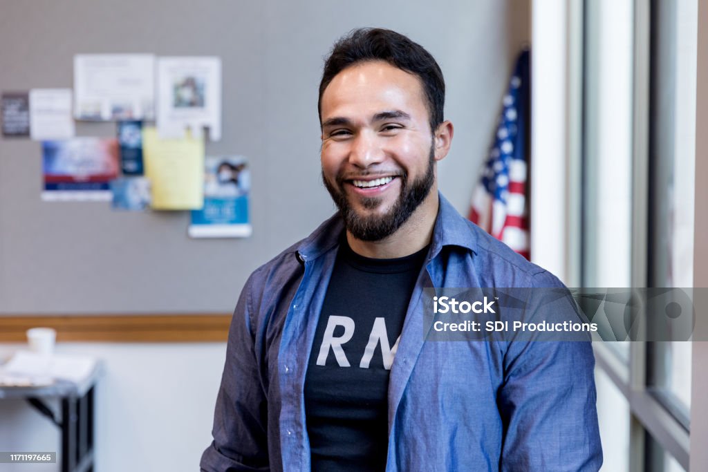 With American flag in background, army vet smiles for camera With the American flag in the background, the mid adult army vet smiles proudly for the camera. Veteran Stock Photo