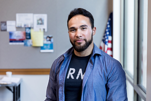 A mid adult army vet poses for a portrait in front of the American flag.