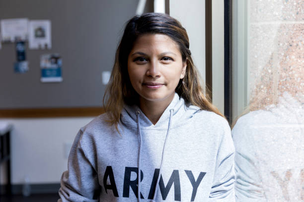 Attractive mid adult female army vet stands in sunlit window An attractive mid adult female army vet stands in a sunlit window for a portrait. self sacrifice stock pictures, royalty-free photos & images