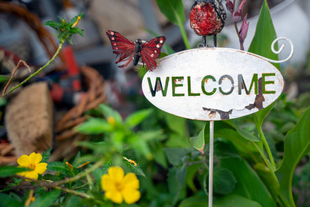 Photo of white welcome signboard and greenery area.  There is no people in the frame. Shoot in outdoor. The photo was shoot in a garden.