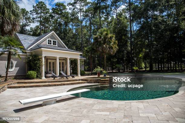 Custom Pool House Behind A Landscaped Estate With A Large Swimming Pool And Hot Tub Stock Photo - Download Image Now