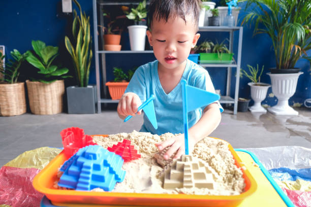 asiatische 3 - 4 jahre alte kleinkind junge spielen mit kinetischen sand in sandkasten zu hause, feinmotorik entwicklung, montessori bildungskonzept - sandbox child human hand sand stock-fotos und bilder