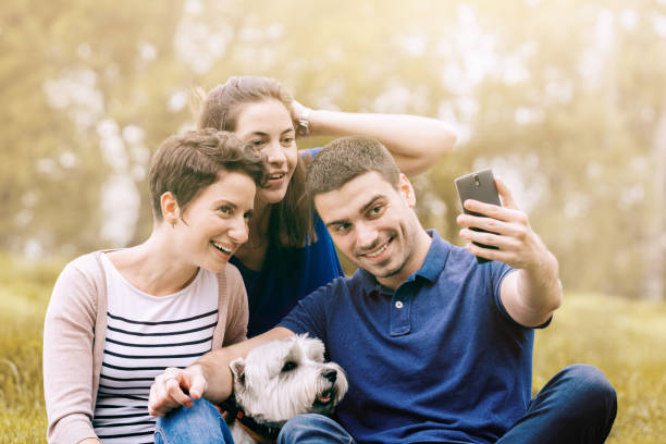 istock Three friends with dog taking selfie 1171217425