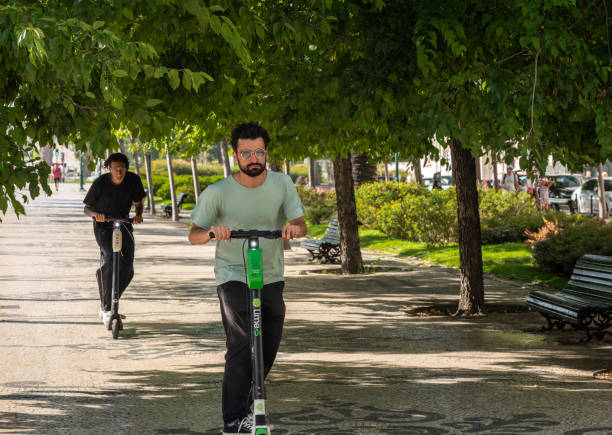 People riding a Lime electric scooter along Liberty Avenue Lisbon, Portugal - 9 August 2019: People riding a Lime S electric scooter along Avenida da Liberdade in Lisboa lime scooter stock pictures, royalty-free photos & images