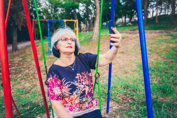 istock Senior Woman on swing taking selfie. 1171230447