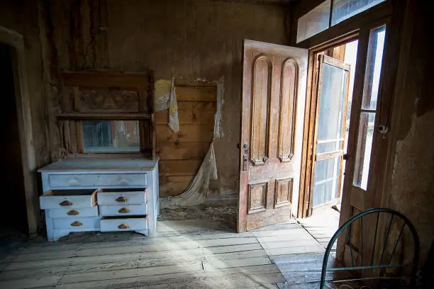 Open front door and empty dusty drawers of an abandoned house
