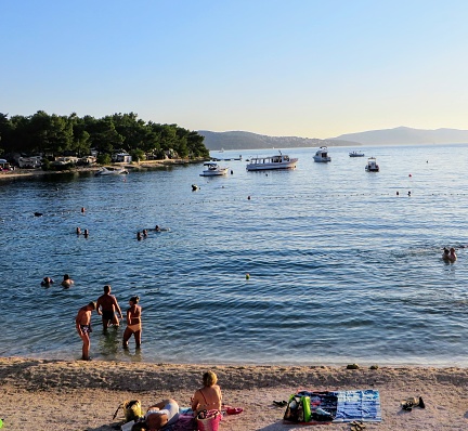 Trogir, Croatia - July 6th, 2019: A beautiful amazing view of Okrug Gornji beach on Otok Ciovo or Ciovo island beside Trogir, Croatia.  Locals and tourists are enjoying the waters as the sun sets.