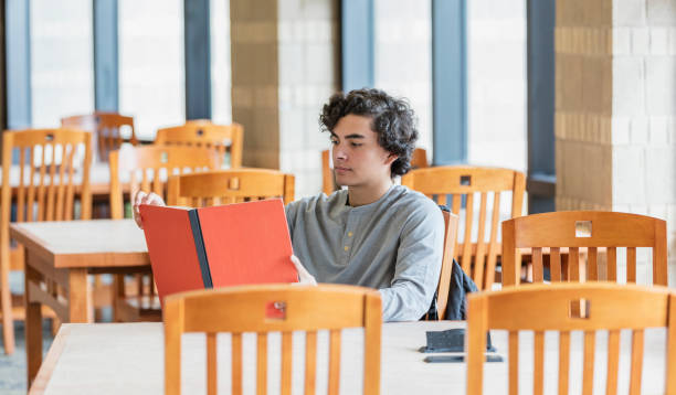 istock Hispanic teenage boy reading in library 1171241405