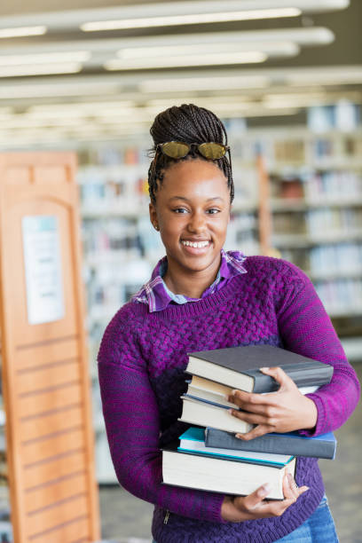 studente delle scuole superiori afro-americane con pila di libri - photography teenagers only vertical teenager foto e immagini stock