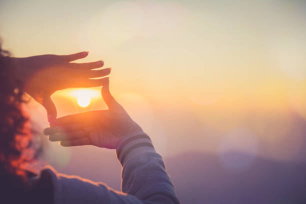 a mulher que faz o frame redondo o sol com suas mãos no nascer do sol, conceito futuro da idéia do planeamento. - calcular - fotografias e filmes do acervo