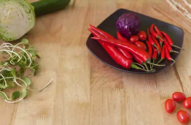 Red chilli with tomato and purple cabbage on  black dish,wooden background